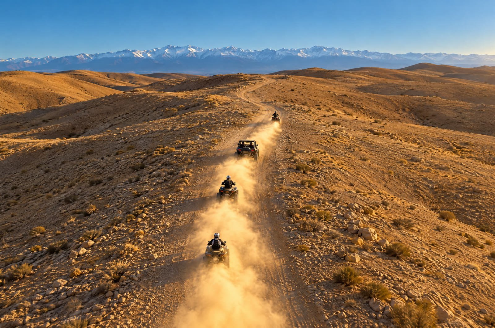 Quads and a buggy on a desert track in Agafay, with the snowy Atlas mountains behind